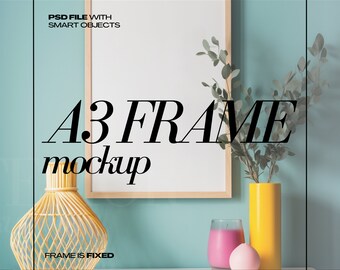 May include: An A3 frame mockup with a light wood frame, displayed on a white shelf against a teal wall. Decorative items include a yellow vase, a pink candle, and a woven decorative object. Text on the image reads "PSD FILE WITH SMART OBJECTS" and "A3 FRAME mockup".