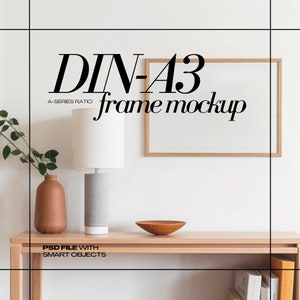 Könnte beinhalten: Eine Holzkonsolentisch mit einer Lampe, einer Vase und einer Schale. Ein gerahmter Mockup befindet sich an der Wand. Der Text "DIN-A3 frame mockup" wird über dem Rahmen angezeigt. Der Text "PSD FILE WITH SMART OBJECTS" wird darunter angezeigt.
