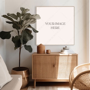 May include: A square framed picture with the text "YOUR IMAGE HERE" hanging on a white wall above a light brown wicker cabinet with two doors. A potted plant is on the left side of the cabinet and a wicker chair is on the right side.