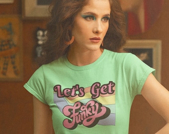 Könnte beinhalten: Eine Frau trägt ein grünes T-Shirt mit dem Text "Let's Get Funky" in einer Retro-Schrift. Sie trägt auch einen Blumenrock und hat ihre Haare zu einem Bouffant gestylt.