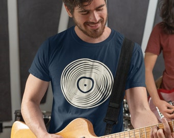 Op de afbeelding: Een man draagt een donkerblauw t-shirt met een witte vinylplaat-afbeelding en speelt een elektrische gitaar. De gitaar is bruin met een zwarte slagplaat. De man draagt een zwarte gitaarband.