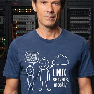 Könnte beinhalten: Marineblaues T-Shirt mit weißem Text und einer Cartoon-Illustration. Der Text lautet "Papa, woraus bestehen Wolken?" und "Linux servers, mostly". Das Bild zeigt einen Vater und ein Kind mit einer Wolke.