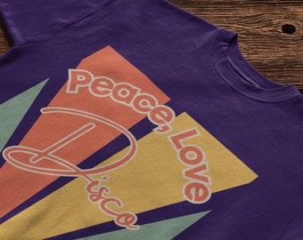 May include: Purple sweatshirt with a retro-style graphic design featuring a record player, the words "Peace Love Disco" in a colorful font, and a geometric pattern in shades of green, yellow, and orange.