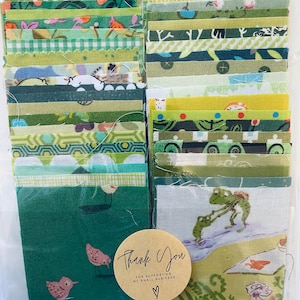 May include: A selection of green fabric squares in diverse patterns, such as stripes, florals, and geometric shapes. A round sticker with the words "Thank You" is visible. The fabric squares are packaged in a clear plastic bag.