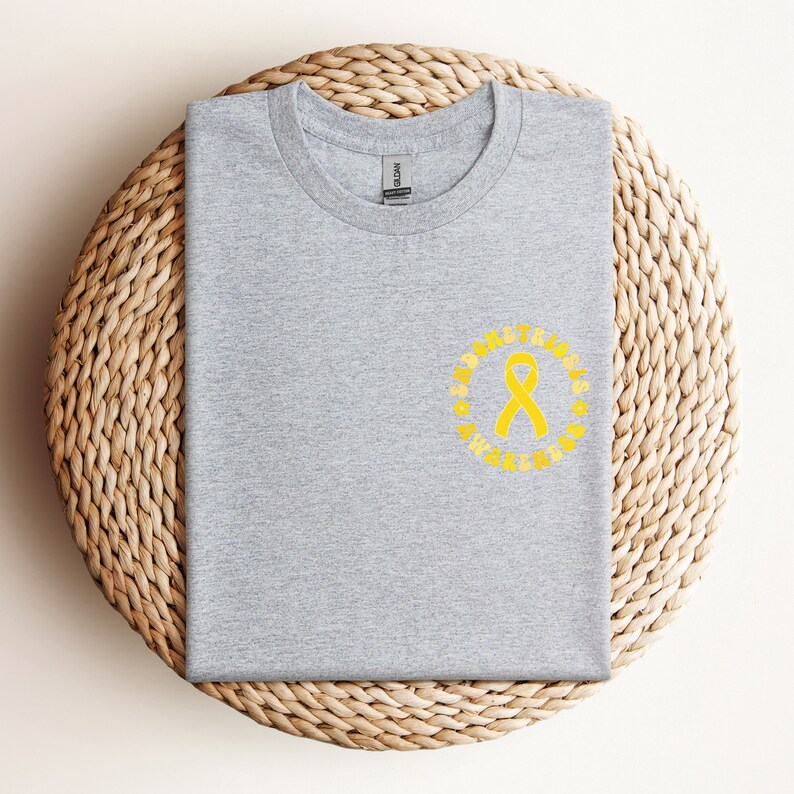 May include: Gray t-shirt with a yellow ribbon and the text "ALBINISM AWARENESS" in a circle around the ribbon.