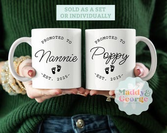 May include: Two white ceramic mugs with black text and a footprint design. The mugs read "Promoted to Nannie - Est. 2025" and "Promoted to Poppy - Est. 2025".