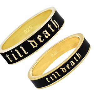 Puede incluir: Dos anillos dorados con bandas de esmalte negro. Los anillos tienen el texto "till death" en una fuente gótica. Los anillos están marcados con "925".