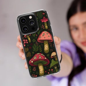 Pode incluir: Uma capa transparente para telefone com um design de cogumelos coloridos. A capa apresenta cogumelos vermelhos, amarelos, verdes e marrons sobre um fundo verde escuro.