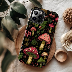 K&ouml;nnte beinhalten: Eine schwarze Handyh&uuml;lle mit einem bunten Pilz- und Blumendesign. Die H&uuml;lle hat einen Ausschnitt f&uuml;r das Kameraobjektiv und einen schwarzen Hintergrund.