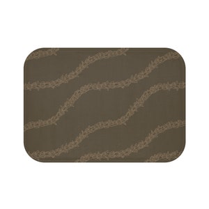 May include: A brown rectangular bath mat with a pattern of light brown floral wreaths.