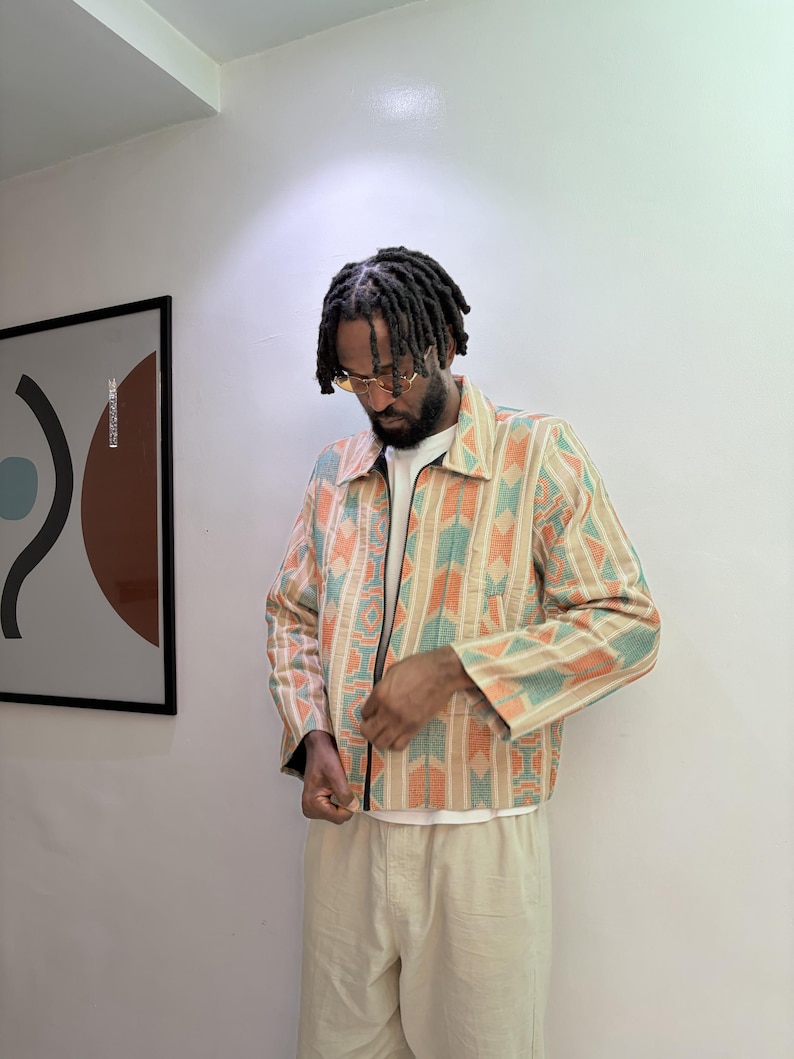 Puede incluir: Chaqueta con cremallera y estampado geom&eacute;trico en naranja, turquesa y beige. Se lleva con una camiseta blanca y pantalones beige. El estilo es casual y moderno. El dise&ntilde;o de la chaqueta es llamativo.