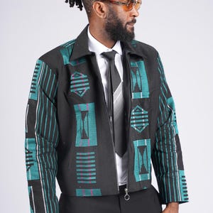 May include: Black jacket with teal and white geometric patterns. The jacket has a zipper closure and a collared neckline. The sleeves and front panels feature a repeating design. The jacket is worn over a white shirt and a black tie.