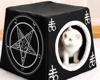 May include: A black cat bed with a white pentagram and the words "For Different Pets But the Same Warmth" on the front. A white cat is peeking out of the entrance to the bed.