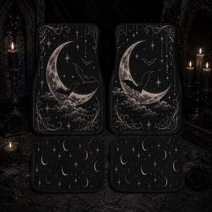 May include: Set of four black car floor mats. The front mats feature a crescent moon design with bats and clouds. The rear mats have a pattern of moons and stars. The mats have a gothic, celestial theme.