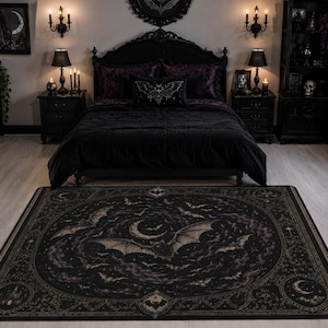 May include: A rectangular area rug featuring a dark black and muted gold color palette. The design displays a central flying bat surrounded by a swirling celestial pattern of crescent moons, stars, and smaller bats within a circular border.