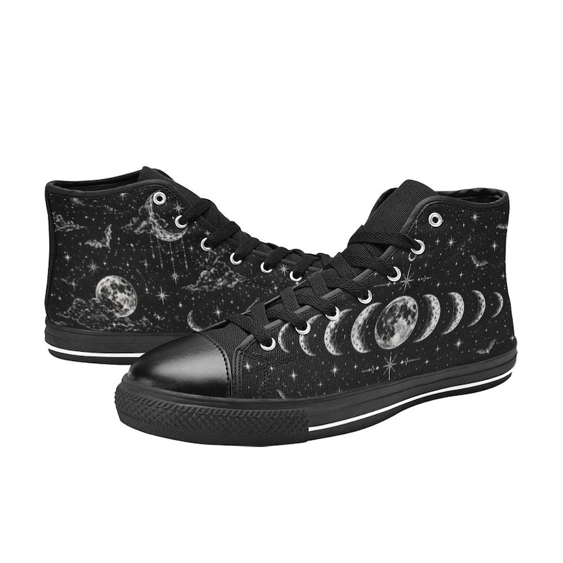 May include: Black high-top sneakers with a celestial design. The shoes feature a black toe cap, laces, and soles with a white stripe. The sides display a moon phase design, stars, clouds, and bats.
