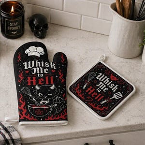 May include: Black oven mitt and pot holder set with the phrase "Whisk Me to Hell" in red and white. The mitt features a devil character and flames. The pot holder has a similar design with kitchen utensils.