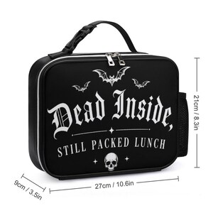 Pu&ograve; includere: Borsa per il pranzo nera con la scritta "Dead Inside, Still Packed Lunch" in bianco. La borsa ha un manico nero, cerniera e tasca laterale. Dimensioni: 27 cm di larghezza, 21 cm di altezza e 9 cm di profondit&agrave;.