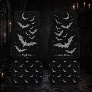 May include: Set of four black car floor mats with a gothic bat theme. The front mats feature a crescent moon and bats in flight, with the text "Night Drive." The rear mats have a repeating bat pattern.