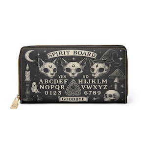 May include: Black zip-around wallet with a spooky Ouija board design. The wallet features cat skull illustrations, a witch hat, and the words "Spirit Board." Additional elements include a candle, ghost, mushroom, and skull.