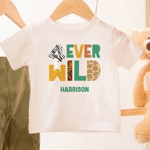 May include: White t-shirt with the text "4ever Wild" in colorful letters with animal print patterns. The name "Harrison" is printed below the text.