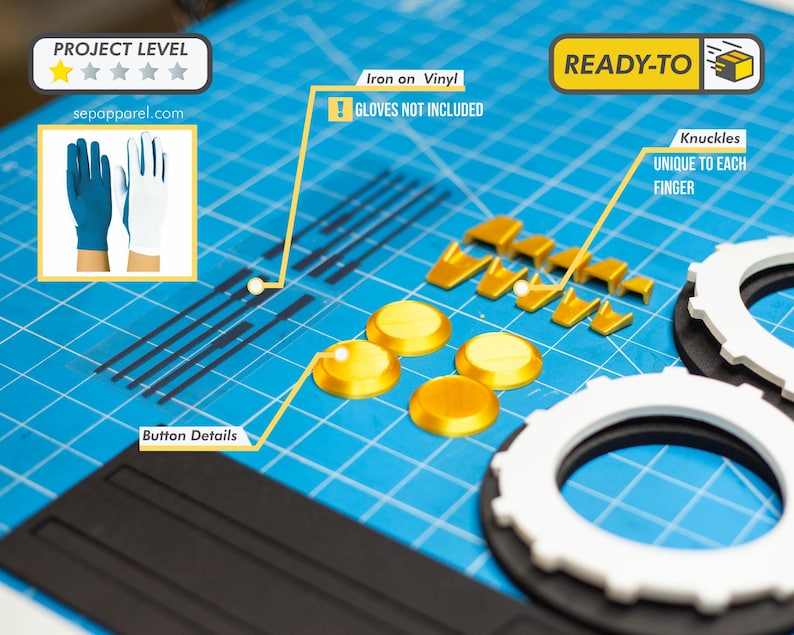 May include: A collection of gold-colored plastic pieces, including buttons and knuckle details, alongside white and black circular components. The image also features a blue cutting mat and a small image of blue and white gloves.