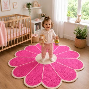 Peut inclure: Un grand tapis rond en crochet fait main en forme de fleur avec des pétales rose vif et un centre couleur crème. Le tapis présente une construction en fil bouclé texturé avec un bord festonné distinct, offrant une surface douce.