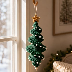 May include: A spiral-shaped crochet Christmas tree ornament in dark green yarn, featuring small white pom-poms along the edges, topped with a mustard yellow crocheted star, and finished with a single wooden bead at the bottom point.