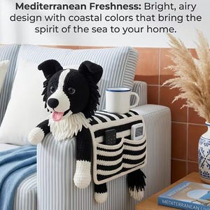 Puede incluir: Un organizador de reposabrazos de ganchillo en blanco y negro con forma de border collie, que incluye una cabeza de perro de peluche, una taza blanca sobre el lomo y dos bolsillos delanteros con un mando negro y uno blanco, en tela a rayas.