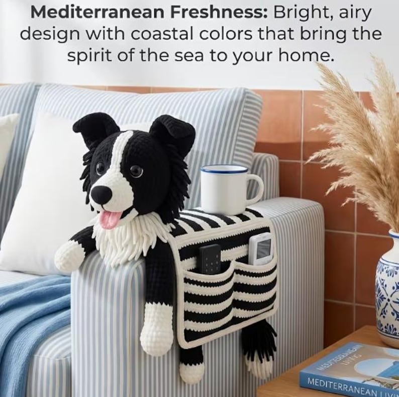 Puede incluir: Un organizador de reposabrazos de ganchillo en blanco y negro con forma de border collie, que incluye una cabeza de perro de peluche, una taza blanca sobre el lomo y dos bolsillos delanteros con un mando negro y uno blanco, en tela a rayas.