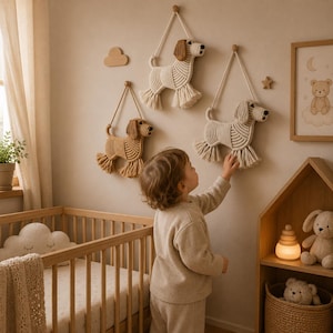 Peut inclure: Trois décorations murales en macramé représentant des chiens dans des tons crème et beige, chacune dotée d'un corps en corde nouée, d'une queue et de pattes à franges, et d'une boucle de suspension. Elles sont fixées à des chevilles en bois.