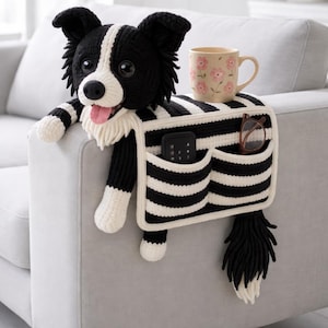 May include: A black and white striped dog-shaped couch arm organizer with pockets. The dog has a pink tongue, black eyes, and a white and black striped body. A mug with pink flowers and a remote control and glasses are in the pockets.