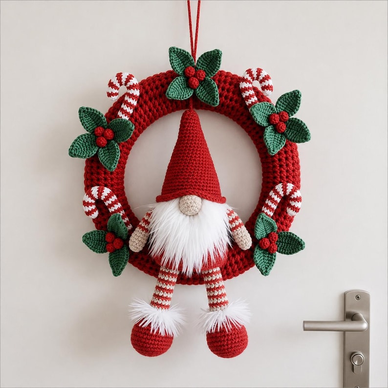 May include: A crocheted Christmas wreath featuring a red circular base adorned with green holly leaves, red berries, and red and white candy canes. A gnome with a red hat, white beard, and striped legs hangs from the center of the wreath.