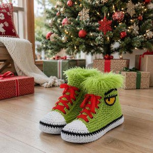 May include: A pair of lime green crochet high-top sneakers featuring fuzzy green trim at the ankle, bright red laces, white toe caps, and a black-outlined yellow eye graphic on the side of each shoe, set against a festive holiday background.