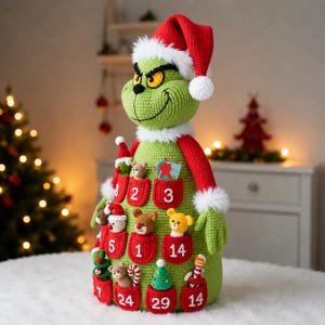 May include: A green crocheted character doll wearing a red Santa hat with white trim. The body features multiple red pockets, each embroidered with a white number, containing small crocheted figures like bears, trees, and candy canes.