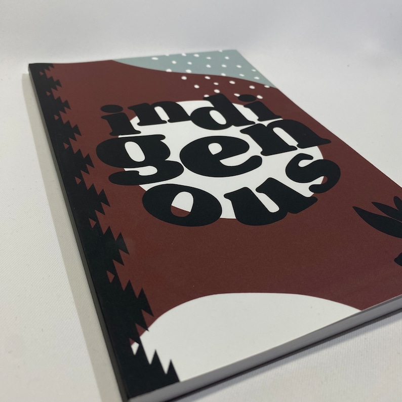 May include: A brown notebook with a black and white geometric design on the cover. The word "indigenous" is printed in large, black letters on the cover.