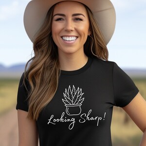 May include: A black t-shirt with a white graphic of a potted succulent plant and the text "Looking Sharp!"
