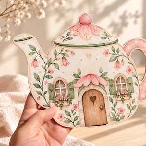 May include: A flat, teapot-shaped decorative cutout featuring a painted illustration of a cottage. The design includes a brown arched door with a heart cutout, two windows with green shutters, pink flower accents, and green vines on a cream background.