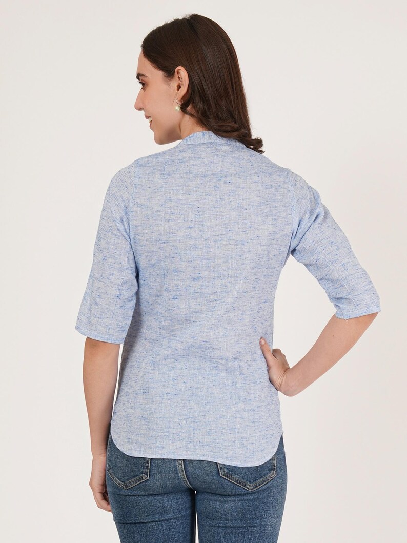 May include: A light blue linen shirt with a mandarin collar and three-quarter sleeves. The shirt is slightly fitted and has a textured look.