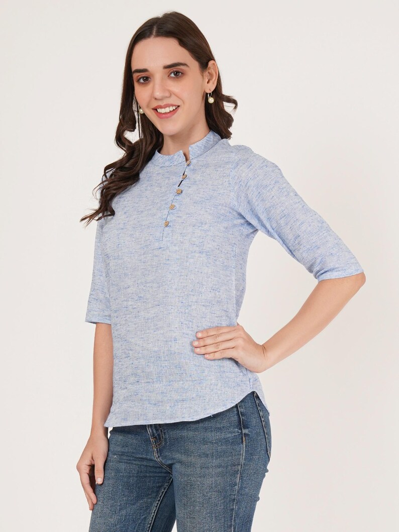 May include: A light blue linen top with a mandarin collar and three button closure. The top has a slightly fitted silhouette and three-quarter sleeves.