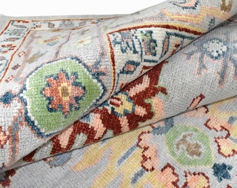 May include: A light blue rug with a floral pattern in shades of pink, green, yellow, and brown. The rug has a traditional design with intricate details.