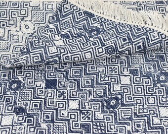 May include: A white and blue geometric patterned rug with fringe. The rug has a woven texture and a modern design.