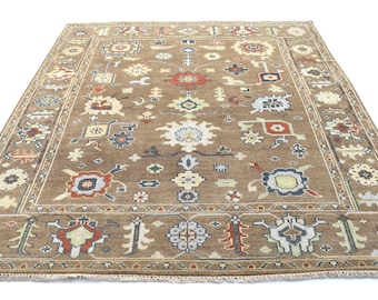 May include: A brown rug with a traditional Persian design. The rug has a central medallion and a border with intricate floral and geometric patterns. The rug is made of wool and has a fringe.