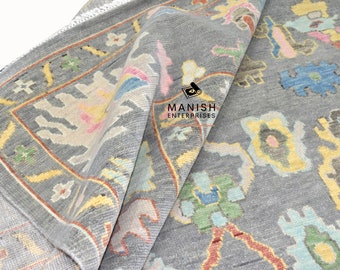 May include: A gray rug with a colorful geometric pattern. The rug has a fringe border and is folded in half. The text "MANISH ENTERPRISES" is visible in the lower center of the image.