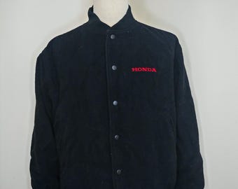 May include: Black Honda bomber jacket with a button-up front and a ribbed hem and cuffs. The Honda logo is embroidered in red on the chest. The jacket is displayed on a mannequin.