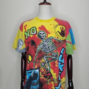 May include: A vintage graphic t-shirt with a skeleton design. The shirt features a yellow, red, and blue color scheme with the words "NO" and "BODY GLOVE" visible. The design includes a skeleton and text on the sleeves.