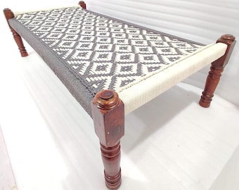 May include: A handcrafted daybed with a woven top featuring a geometric diamond pattern in gray and white. The bed frame is made of dark brown wood, with turned legs and rounded corner posts. The bed measures approximately 60 inches long.