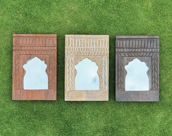 Può includere: Tre specchi decorativi rettangolari con aperture ad arco e cornici in legno intagliato. Le cornici sono in tonalità marrone, bianco sporco e grigio. Gli specchi sono posti su uno sfondo verde.