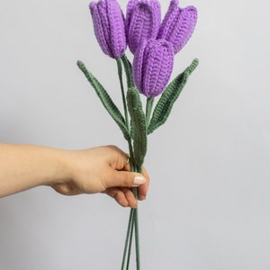 May include: A bouquet of four crocheted purple tulips with green stems.