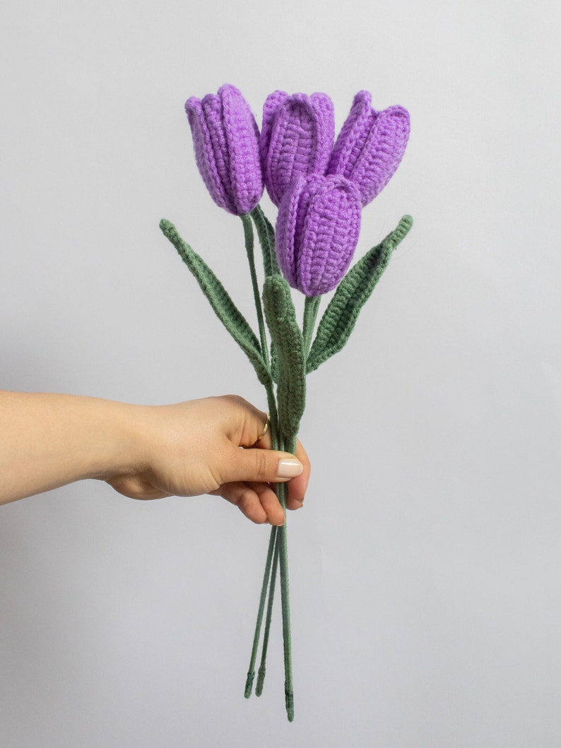 May include: A bouquet of four crocheted purple tulips with green stems.